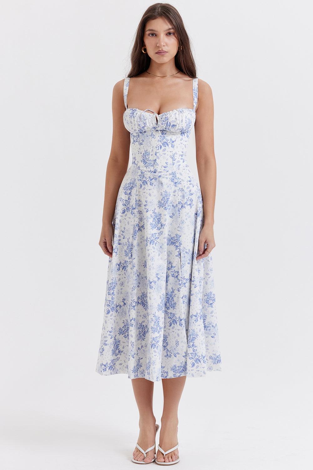 Frau in geblümtem Sommerkleid, beige mit rosa und lila Blumenmuster, ärmellos, elegantes Design.
